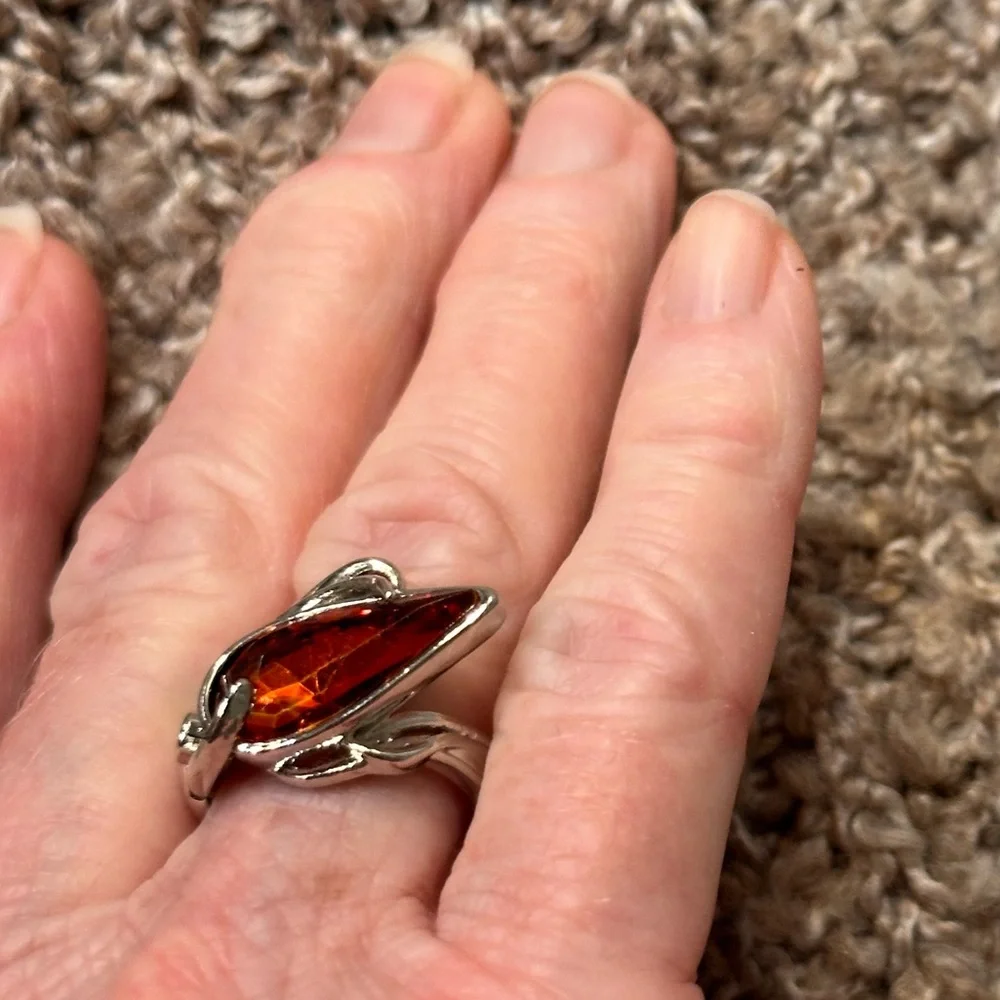 Ring in silver metal intricate with teardrop shaped amber color stone